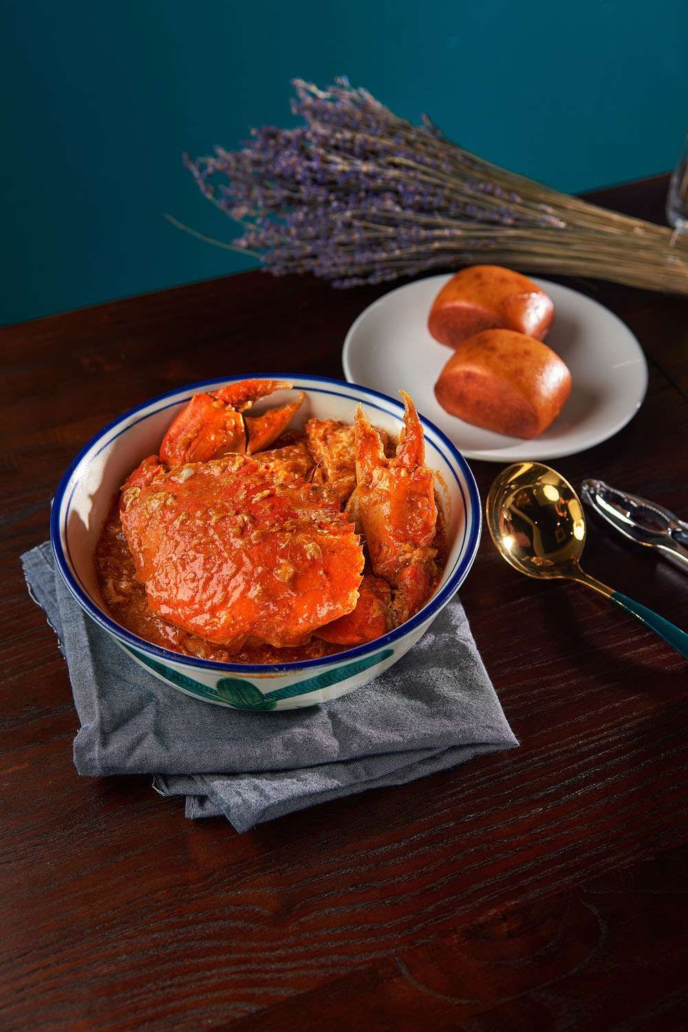 Chilli Crab: a whole mud crab in red chilli gravy in a blue-rimmed bowl, with fried mantou on a plate beside it
