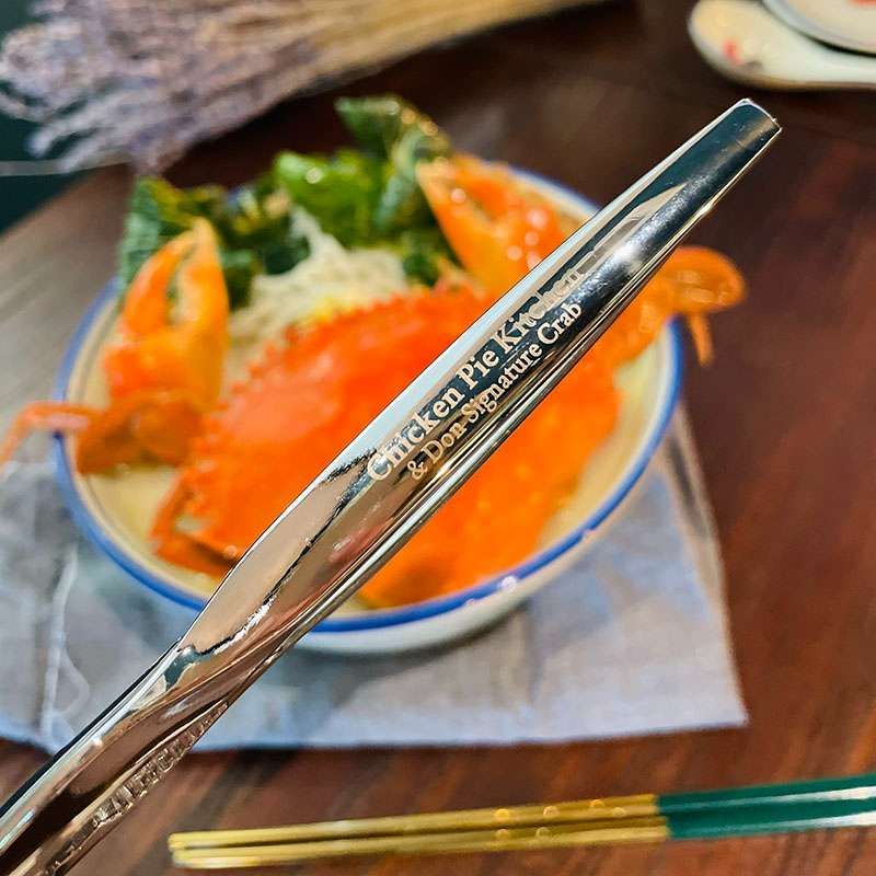 The limited edition metal crab cracker lying over a bowl of crab bee hoon soup